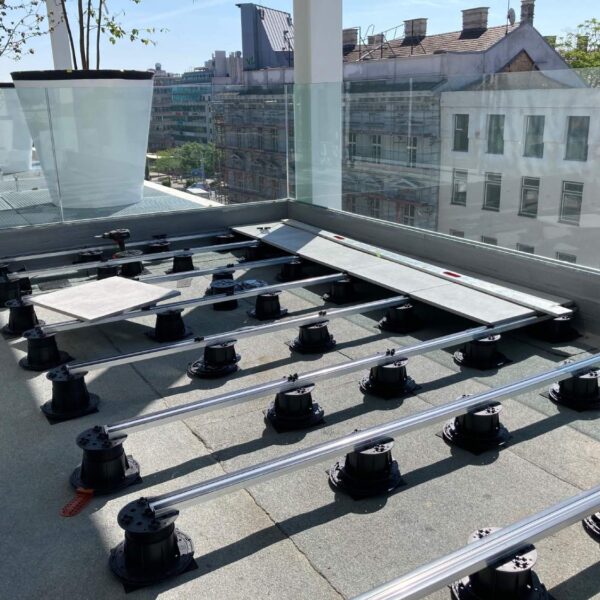 Rooftop deck with porcelain paver planks on Buzon Easy Rail System with spacer tabs and integrated EPDM shims.