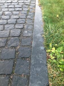 Black Sea Blue Granite cobble-size pavers spaced evenly next to a matching curbstone.