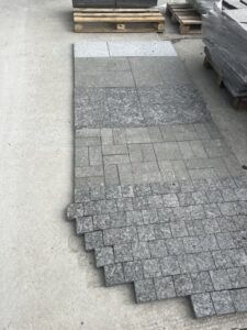 HDG Black Sea Blue Granite samples showing different finishes laid out in the stoneyard for side-by-side comparison.