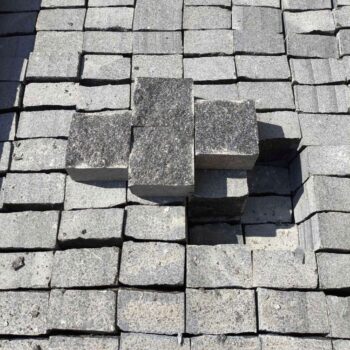 Four light grey granite cobblestones stacked above a larger group on a pallet.