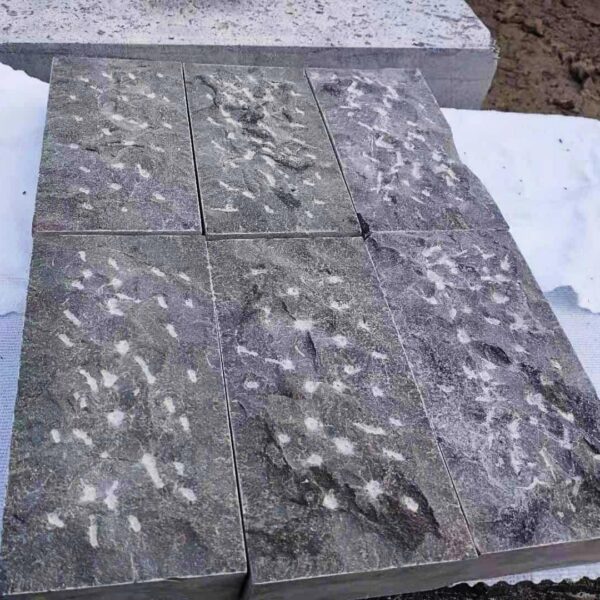 Caviar Blue limestone samples with pineapple stone finish displayed over a sawn-cut surface