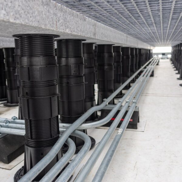 Conduit entering pedestal system and running parallel with granite ballast layout