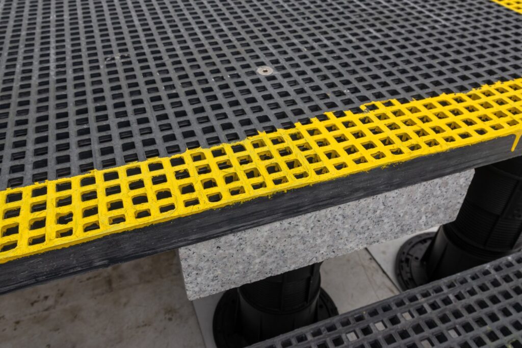 Close-up of grating panel step with flush fastener and ballast on pedestal system