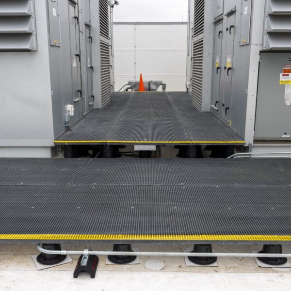 Access platform with step-up and visible conduit routing beneath grating panels