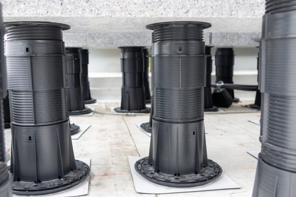 Granite ballast on pedestal supports over slip sheets protecting rooftop substrate