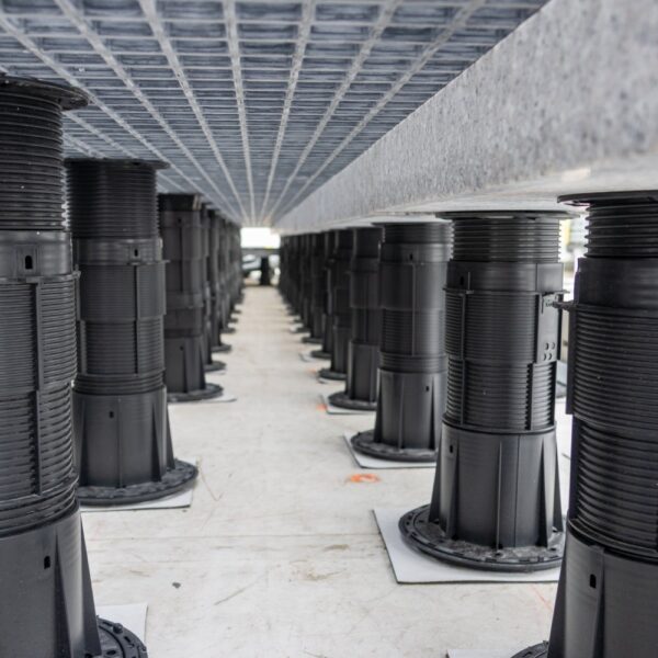 Low view under grating panels showing pedestal rows and granite ballast placement