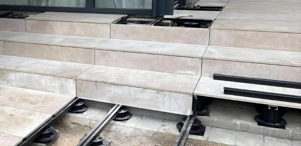 Buzon pedestals and E-BRS rails installed over dirt and concrete substrate to create a raised terrace on uneven ground