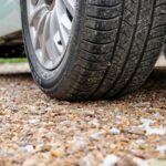 Vehicle parked on a permeable gravel parking pad with stabilized aggregate surface.