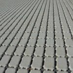 Permeable concrete pavers installed in a tight geometric pattern with built-in spacing for water drainage.