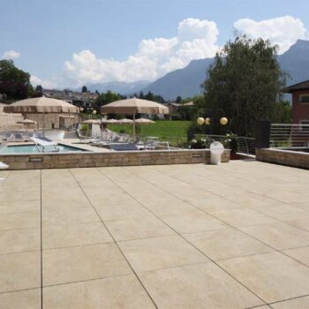 Resort-style swimming pool and sun deck finished with Rosca Gold porcelain pavers.