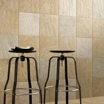 Close-up of Rosca Gold porcelain pavers used on both floor and wall surfaces with black saddle stools.