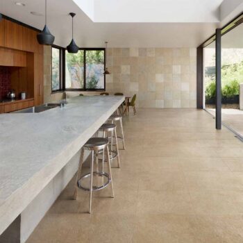 Commercial dining area with floor-to-ceiling glass walls opening onto an outdoor terrace finished with Rosca Gold porcelain pavers.