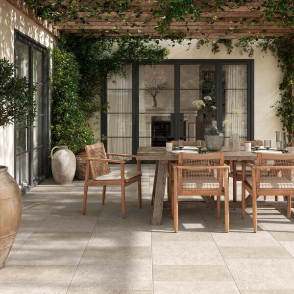 Slate Cream and Slate White 24x24-inch porcelain pavers create a checkerboard pattern beneath a wood pergola with lush greenery and planters.